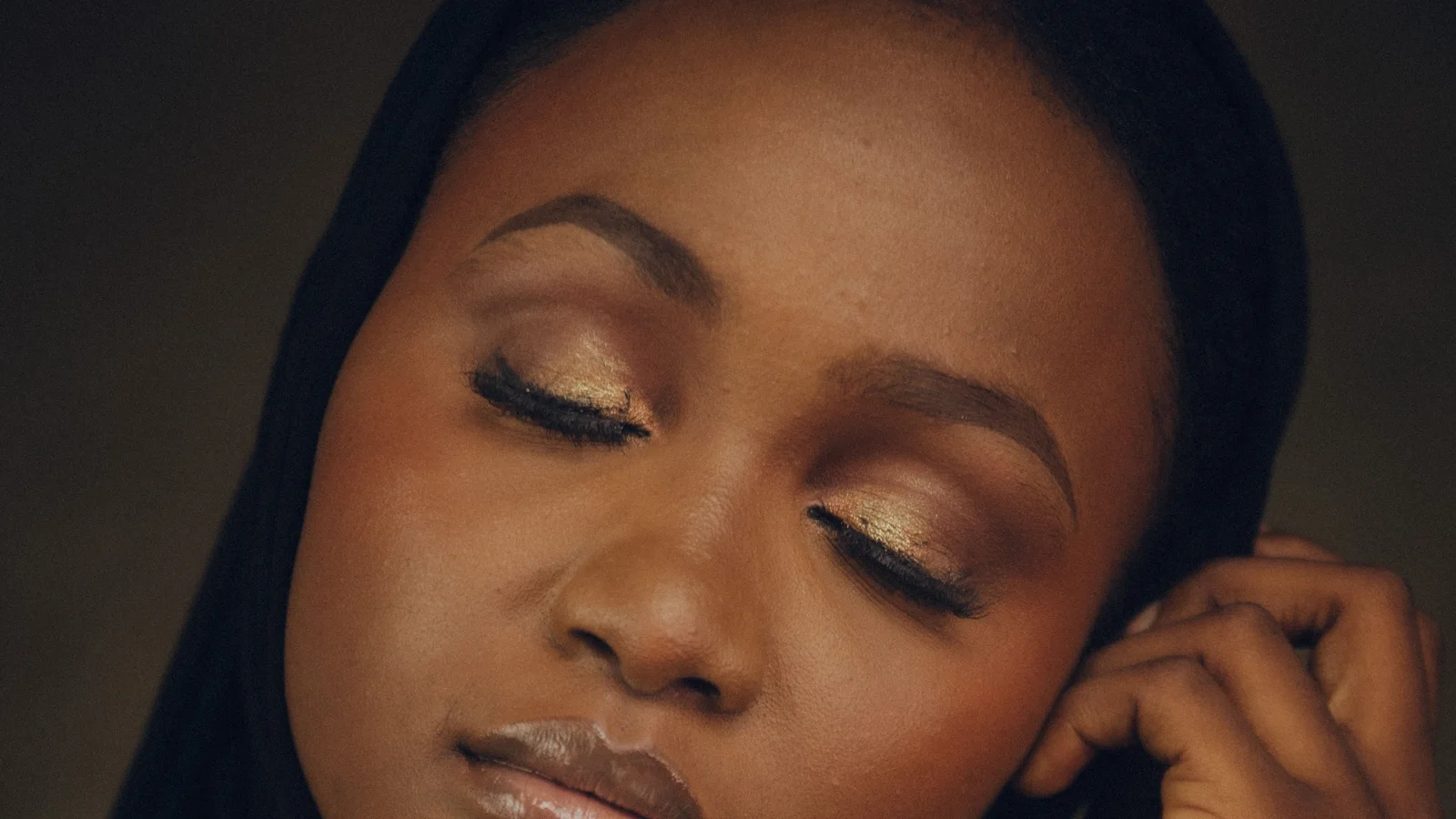 Portrait of a woman wearing a black head covering with her eyes closed and eye make-up visible.