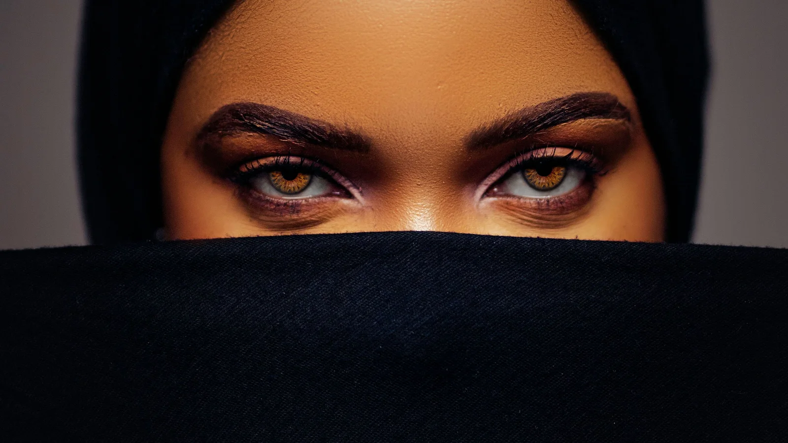 Portrait of a woman with a black covering over her hair and lower face.