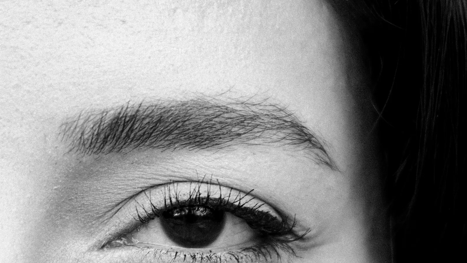 Black-and-white close-up of one side of a woman's face and eye.