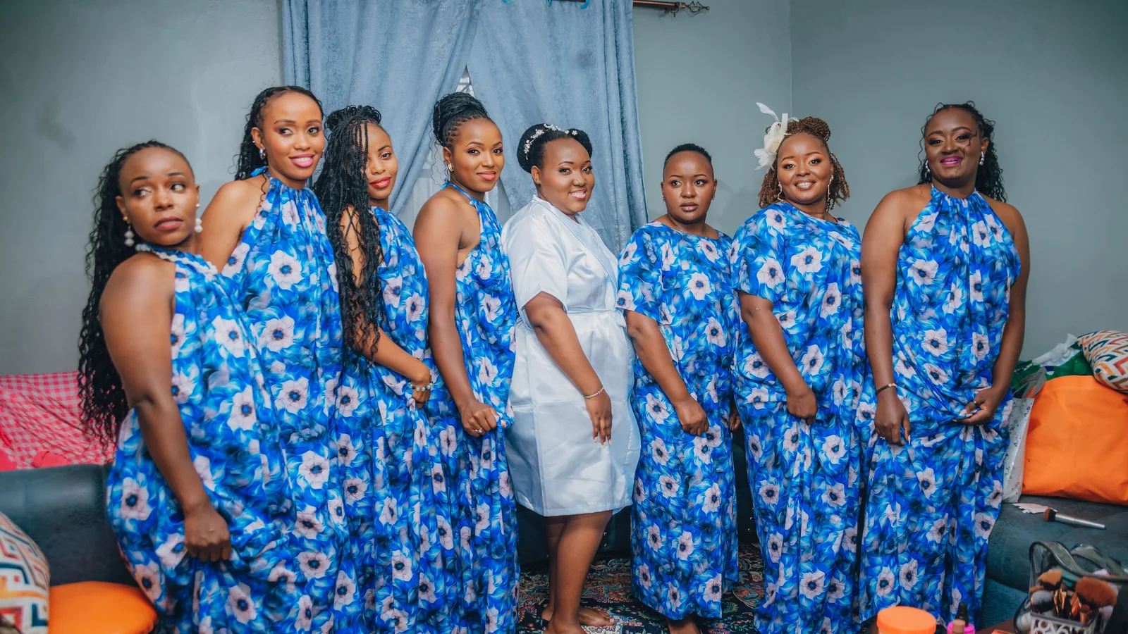 A group of women wearing blue patterned occasion dresses indoors.