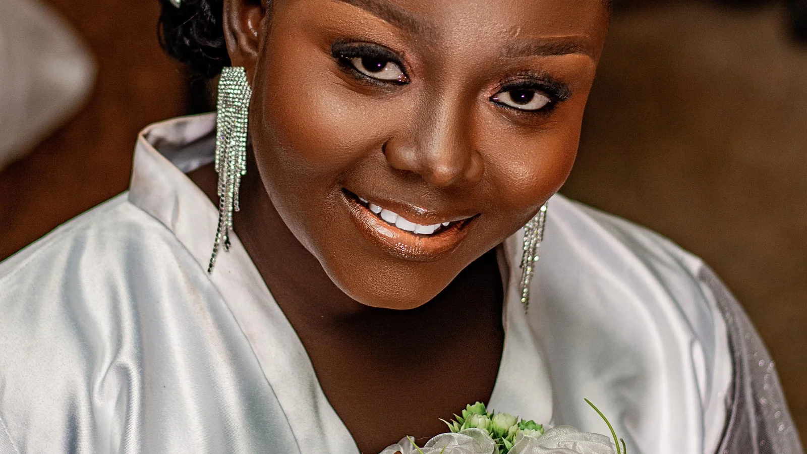 A woman holding a bouquet with her face and bridal jewellery in view.