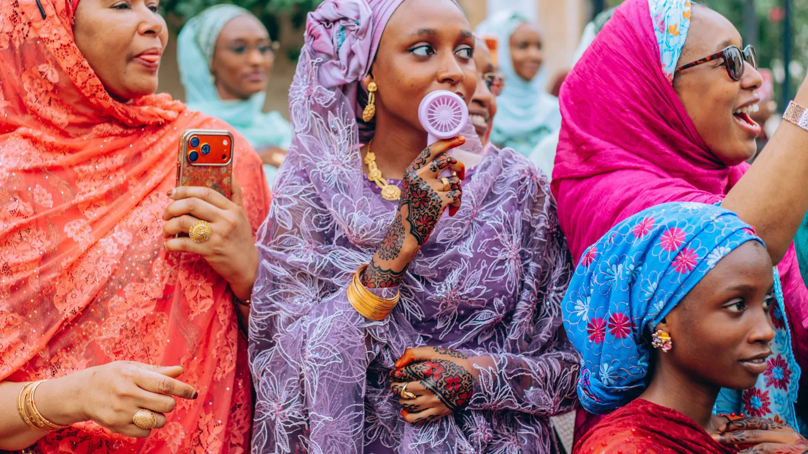 A group of women in colourful patterned outfits gathered outdoors.