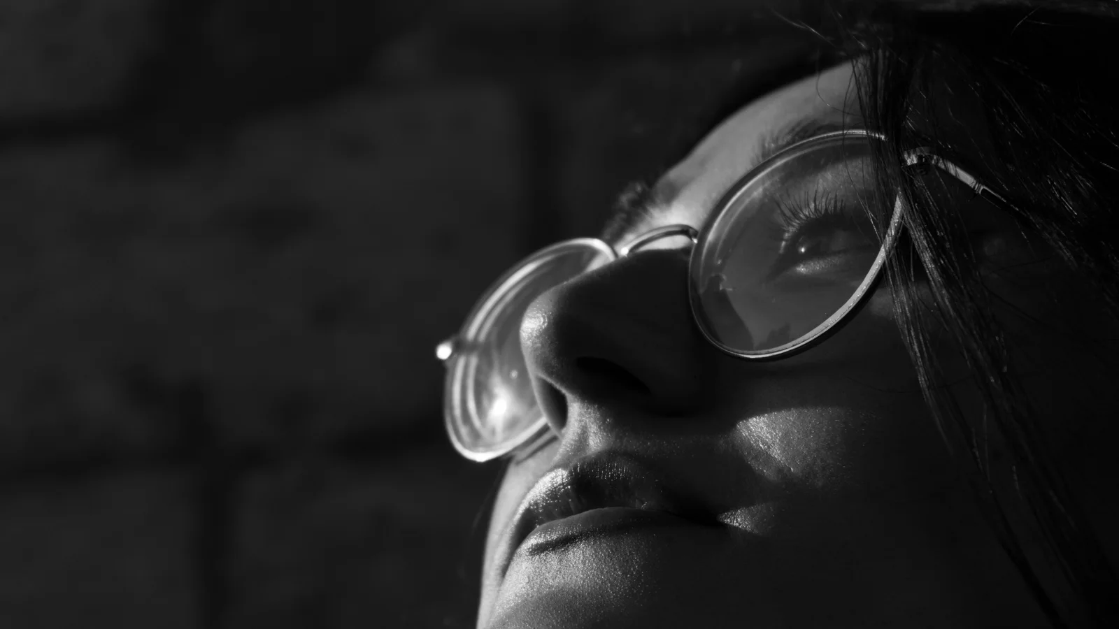 Black-and-white close-up of a woman wearing rounded glasses.
