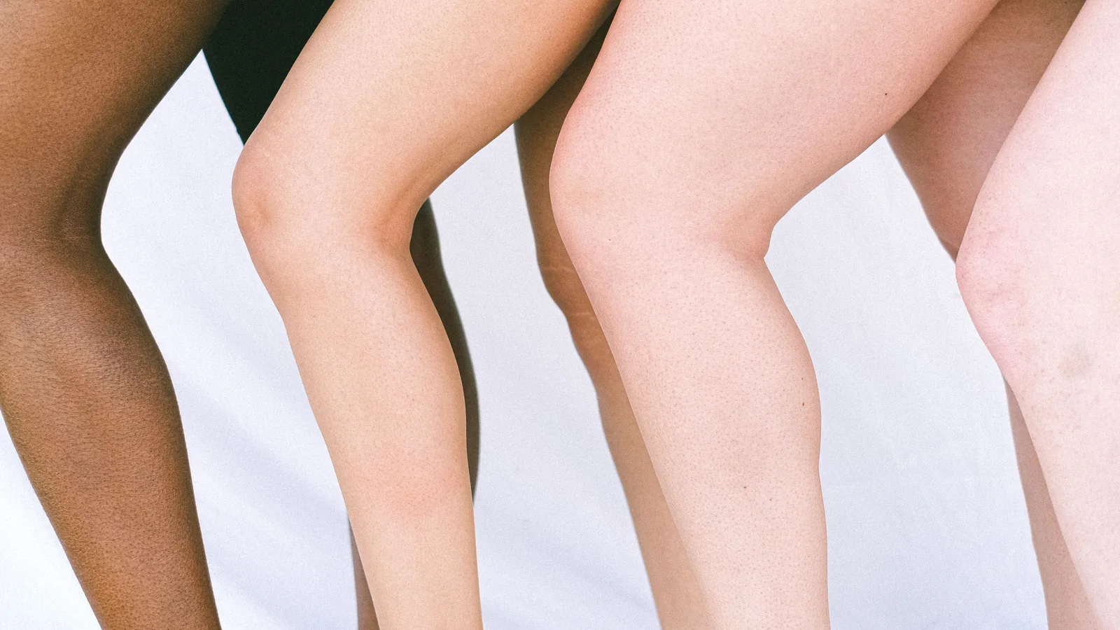 Several people standing with their knees and lower legs visible against a pale background.