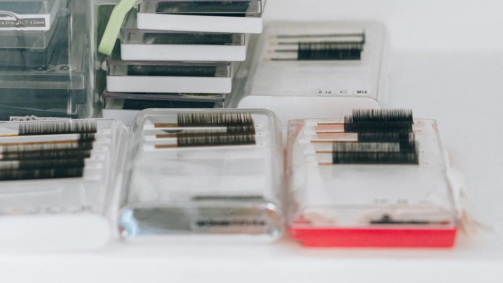 Clear lash-storage trays containing rows of false eyelashes.