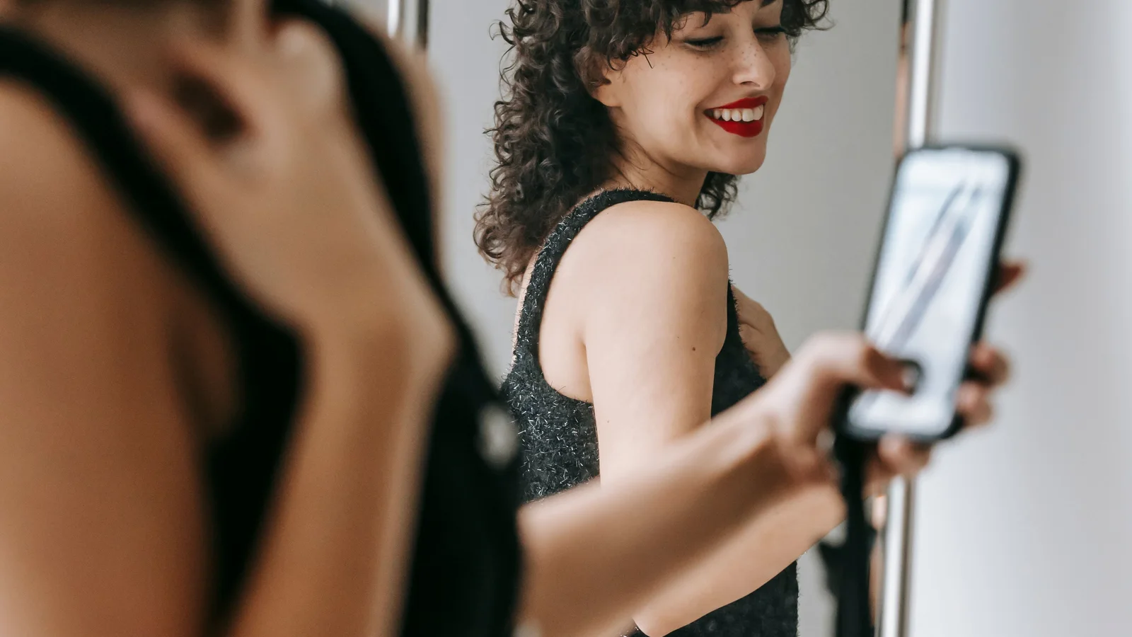 A woman holding a phone towards her reflection in a mirror.