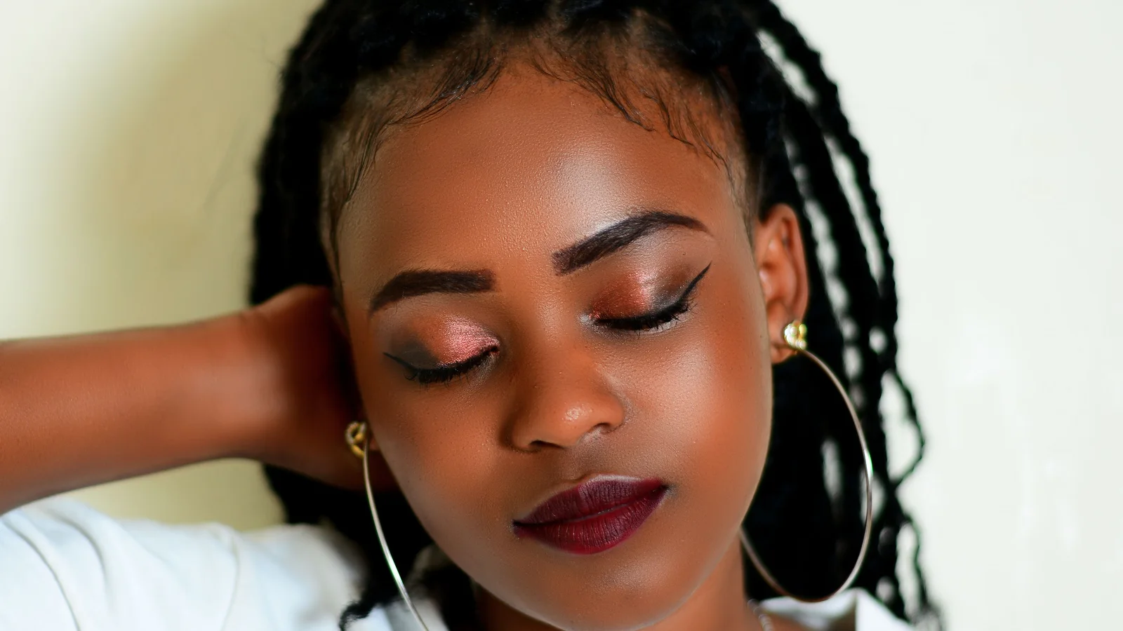 A woman with closed eyes, hoop earrings and softly blended eye make-up.