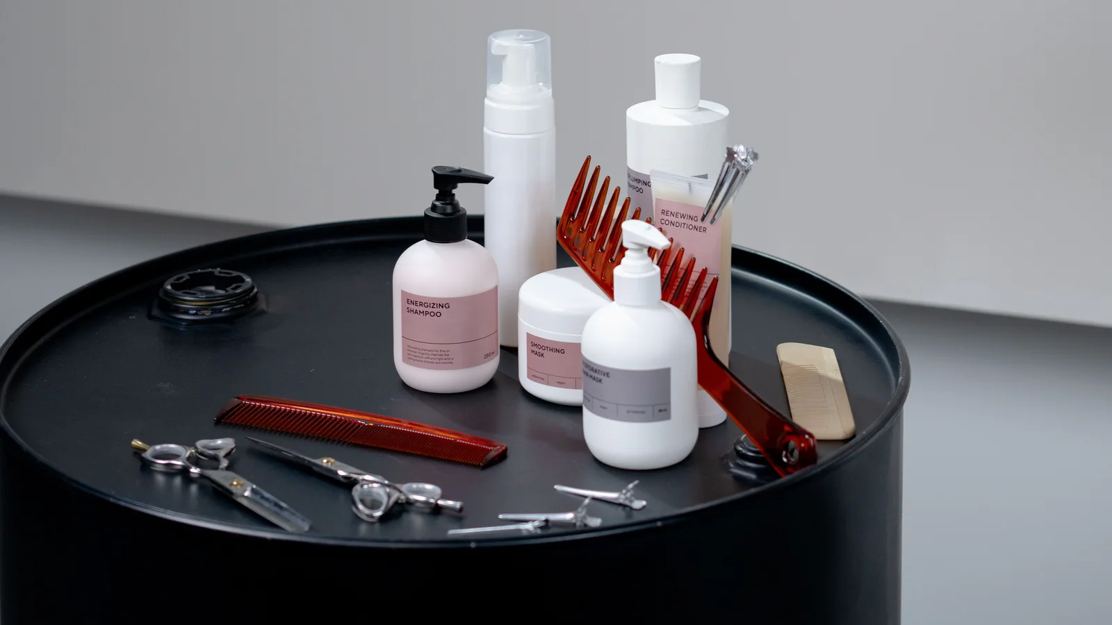 Hair-care bottles, combs and brushes arranged on a dark round table.