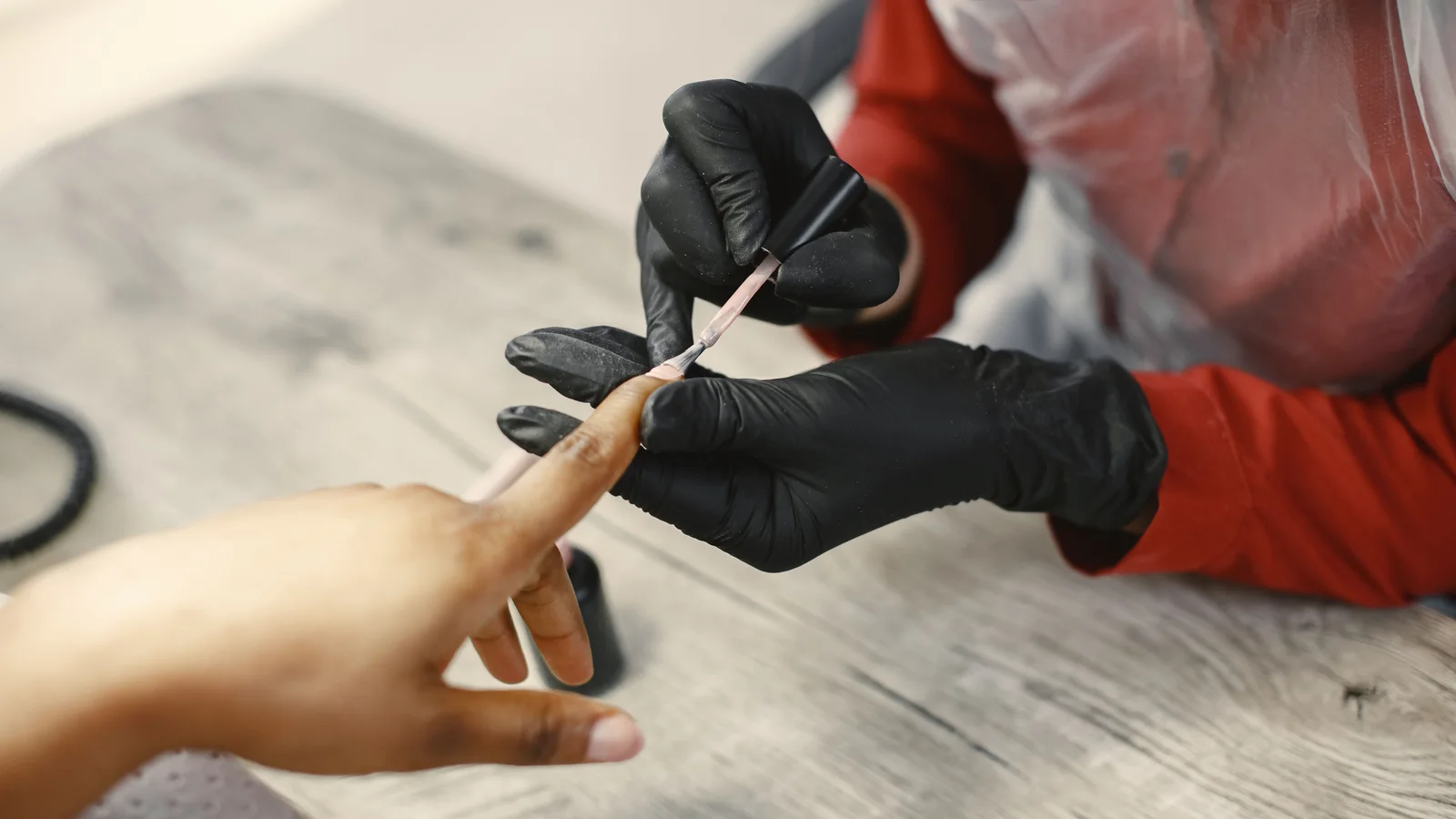 A technician applying a product to a fingernail with a small brush.