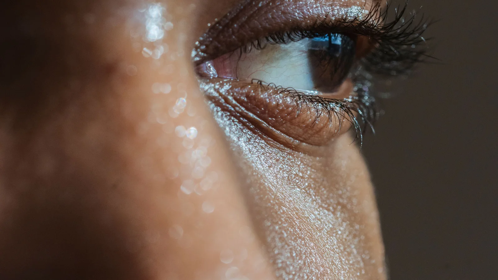 Close-up of a woman's cheek, nose and eye with visible natural skin texture.