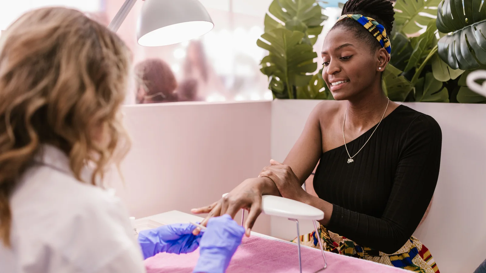 A woman having a manicure at a bright salon table.