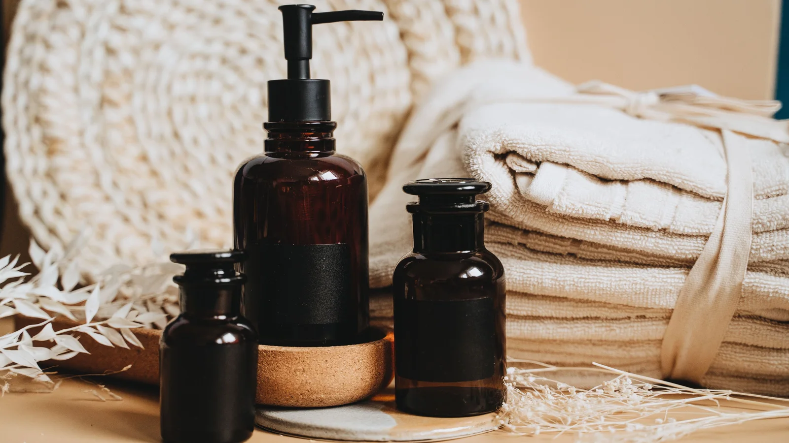 Amber pump bottles and folded pale towels arranged together.