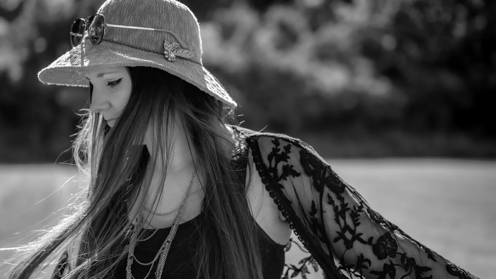 Black-and-white photograph of a woman wearing a wide-brimmed hat and a lace shawl outdoors.