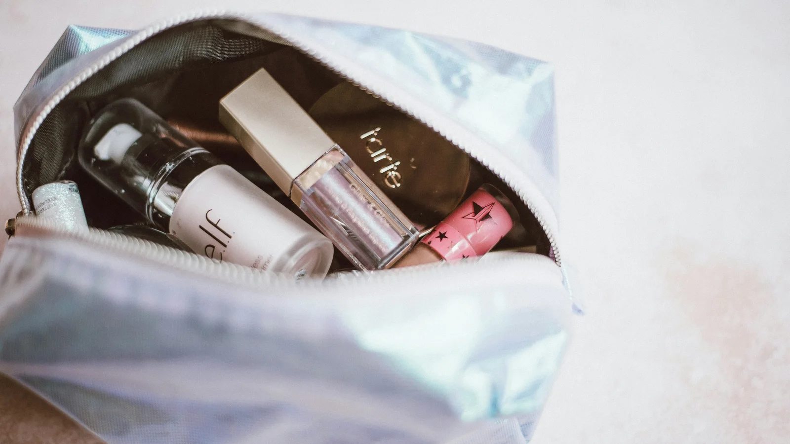 An open pale make-up bag containing bottles and small toiletries.